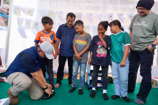 Wakil Bupati Aceh Tamiang Ismail menyaksikan penyerahan sepatu bagi anak penghuni Huntara Aceh Tamiang oleh Direktur Utama PTPN IV PalmCo. Selain menyiapkan lahan untuk pembangunan hunian, dukungan psikososial terus diperkuat PTPN IV melalui pemberian sepatu sekolah dan peluncuran Sekolah Darurat bekerjasama dengan benihbaik.com yang didirikan oleh Andy F Noya